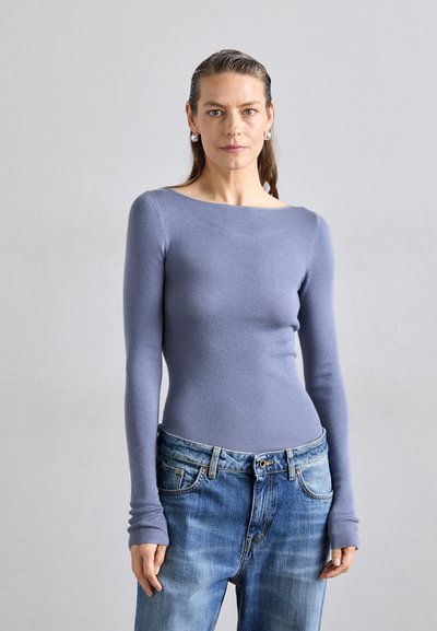 Light purple long-sleeved top with a boat neckline, fitted design, paired with light blue denim jeans with a relaxed fit and subtle fading.