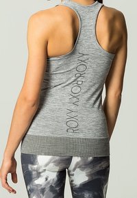 Camiseta gris de tirantes con diseño de espalda nadador, con un dobladillo acanalado y un detalle del logo vertical en la parte posterior. Textura de tela suave y con elasticidad.
