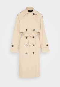 Béžový trench coat s krátkým střihem, dvouřadovým černým knoflíkem, páskem a ramenními vycpávkami; hladká textura látky.
