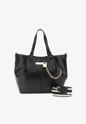Sac à main en cuir noir avec chaîne dorée et plaque logo, deux poignées supérieures, et une bandoulière amovible rayée noir et blanc.