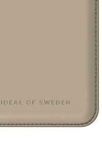 Lys beige telefondeksel med en glatt, blank overflate. Har preget "IDEAL OF SWEDEN"-tekst nederst og kontrasterende søm.