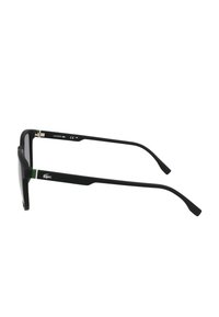 Ochelari de soare negri cu un cadru dreptunghiular elegant, având accente verzi pe brațe și un logo Lacoste proeminent. Finisaj texturat.