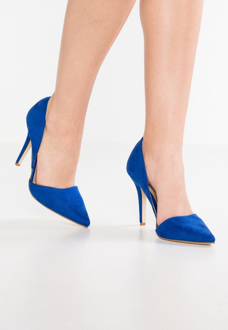 Bottines à talons hauts en daim bleu avec un bout pointu et un design à dos ouvert. Le talon est de style stiletto, offrant une élévation supplémentaire.