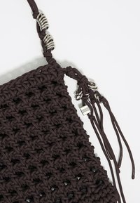 Borsa in tessuto annodato di colore marrone scuro, con dettagli metallici e corde regolabili. Design testurizzato con un motivo a trama aperta.