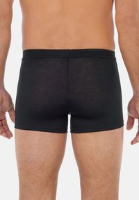 Schwarze Baumwoll-Boxershorts mit eng anliegendem Schnitt, ausgestattet mit glatter Textur, elastischem Bund und genähten Säumen. Ansicht von hinten.
