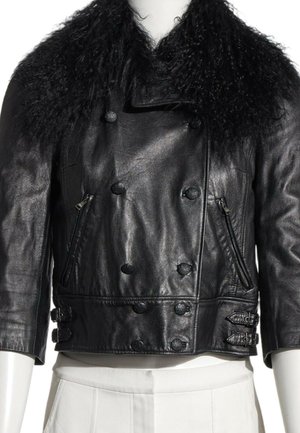 Chaqueta recortada de cuero negro con botones cruzados, bolsillos laterales con cremallera, correas con hebillas y un gran cuello de piel rizado.