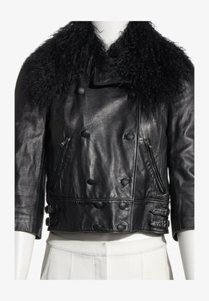 Chaqueta recortada de cuero negro con botones cruzados, bolsillos laterales con cremallera, correas con hebillas y un gran cuello de piel rizado.