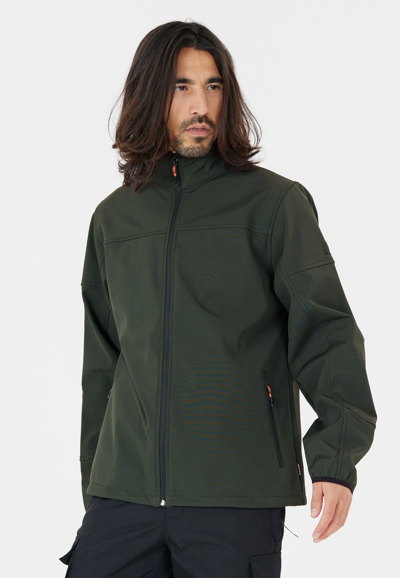 Veste softshell vert foncé avec un col haut, une fermeture éclair intégrale et des poches zippées. Présente une texture lisse et un design minimaliste.