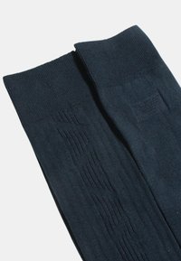 Tmavě modré podkolenky s žebrovanou texturou a diagonálním vyřezávaným vzorem. Hladký materiál zajišťuje pohodlné nošení.