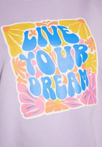 Felpa viola con una grande grafica che presenta il testo "VIVI IL TUO SOGNO" in blu in grassetto, circondata da motivi floreali colorati in rosa e giallo.