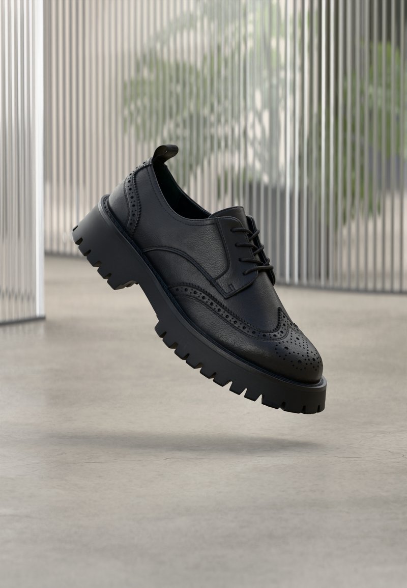 Zwarte leren brogue schoen met geperforeerde details, dikke rubberen zool en vetersluiting. Glad oppervlak met een gepolijste afwerking.