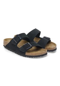 Sandali slide in suede nero con due cinturini regolabili e fibbie metalliche, dotati di un plantare in sughero e una suola in gomma nera testurizzata.