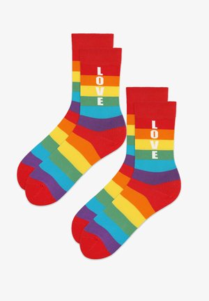 Kolorowe skarpetki w paski z czerwoną mankietą i palcem, z poziomymi pasami w kolorach tęczy oraz napisem "LOVE" na białym tle.