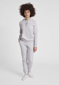 Ljust grå sweatshirt med huva och framficka, i kombination med matchande slim fit träningsbyxor. Båda är tillverkade av mjukt tyg och har muddar i nederkant.