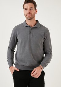Grijs langemouw polo shirt met een kraag, drie knopen aan de voorkant, ribgebreide manchetten en zoom. Kenmerkt zich door een gladde, gestructureerde stof.