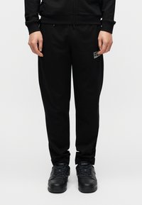 Μαύρο παντελόνι φόρμας από βαμβακερό μείγμα, με άνετη γραμμή, τσέπες στο πλάι και μικρή λεπτομέρεια λογότυπου στο αριστερό μηρό.