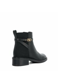 Bottines en cuir noir avec panneau latéral élastique, accent en métal doré et petit talon bloc. Texture lisse avec un design minimaliste.