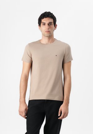 T-shirt beige à manches courtes avec un col rond, fabriqué en tissu doux et extensible, avec un petit logo sur la poitrine.