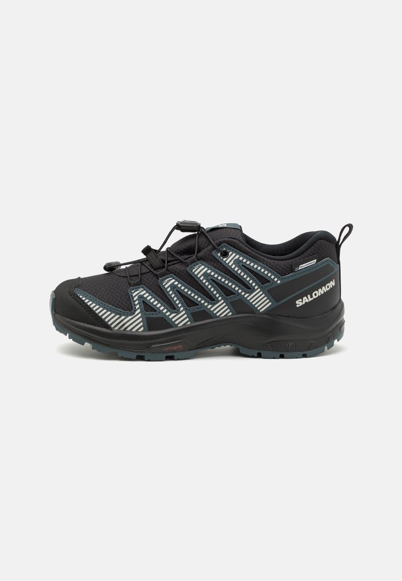 Zapatilla de trail running negra con parte superior de malla transpirable, rayas reflectantes, sistema de cordones elásticos y suela de goma texturizada para mayor agarre.