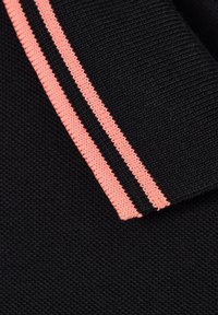 Tela negra con un borde acanalado que presenta dos rayas paralelas de punto rosa a lo largo del puño o dobladillo.