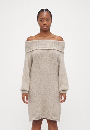Robe pull à épaule dénudée en beige clair, avec de longues manches bouffantes, un col côtelé et une coupe décontractée.