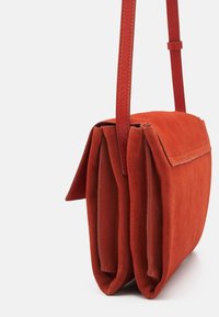 Rode suede schoudertas met een plat ontwerp, voorzien van een enkele schouderriem en een klep. Zachte textuur met twee compartimenten.