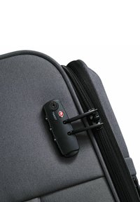 Maleta de tela gris con un candado TSA negro, que presenta una superficie texturizada, un zipper suave y esquinas redondeadas.
