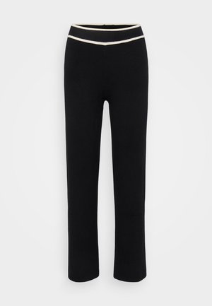 Juodos kelnės su prigludusia forma, pagamintos iš minkštos medžiagos. Savybės - kontrastingas kreminės spalvos juosmuo ir tiesus kelnių kirpimas. Nėra raštų ar akcentų.