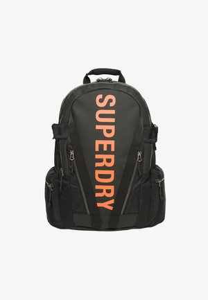 Zwarte rugzak met oranje verticale tekst "SUPERDRY", meerdere ritssluitingvakken en gevoerde schouderbanden.