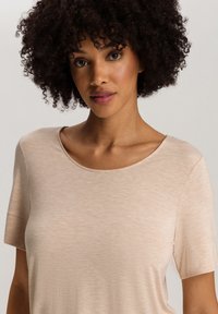 Beige t-shirt met korte mouwen en een ronde hals. Zachte textuur en licht gemêleerde stof. Strak design rond de schouders.