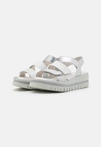 Sandalo bianco e argento con ampie cinghie incrociate, design open toe e sole bianca testurizzata con leggero plateau e bordi scanalati.