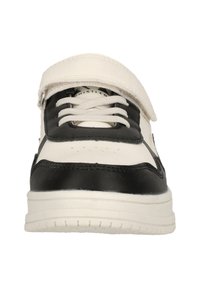 Svart och vit sneaker med en slät läderöverdel, platta skosnören, kardborreband och en texturerad gummisula.