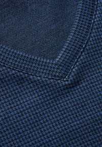 Blauer strukturierter Stoff mit karierter Muster, ausgestattet mit einem runden Halsausschnitt und kontrastierenden Nahtdetails. Weiche Strickzusammensetzung.