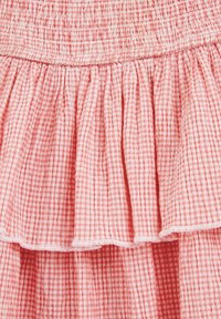Roza gingham krilo z nabrano pasom in plastnatimi naborki, izdelano iz lahkega blaga z mehko teksturo in belim šivanjem.