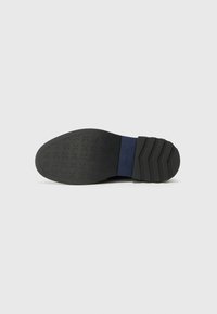 Sort gummisko sål med struktureret overflade, der har et robust design og let hævet hæl. Inkluderer en blå accent ved mellemsålen.