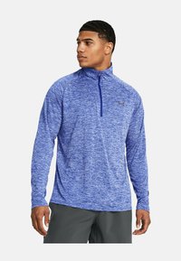 Blauwe sportieve lange mouwen shirt met een half-rits kraag, textuurstof en logo op de borst. Het shirt heeft een gemêleerd patroon.