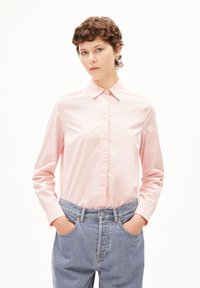 Lichtroze lange mouw shirt met een puntige kraag, voorzien van een knoopsluiting aan de voorkant en een gladde textuur, gecombineerd met hoge blauwe denim jeans.