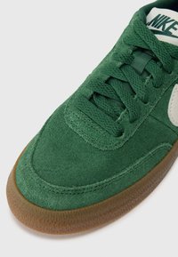 Baskets en suède vert avec des lacets ronds, un accent logo blanc et une semelle en caoutchouc texturé. Tige lisse avec des détails cousus.