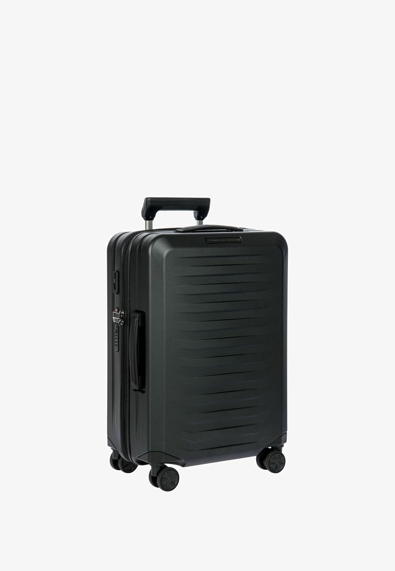 Valise rigide noire avec des rainures verticales, poignée rétractable, quatre roues pour la mobilité et fermeture éclair. Design durable pour les voyages.
