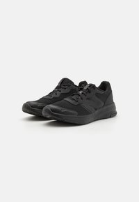 Baskets noires de sport avec tiges en mesh, semelles en caoutchouc, accents texturés et lacets. Conçues pour le confort et le soutien lors des activités physiques.