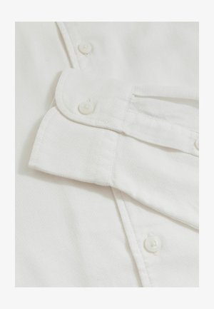 Hvid bomulds skjorte med en tekstureret finish, der har en foldet krave, synlige knapper og en klassisk knapstolpe på forsiden.
