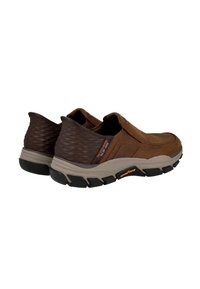 Zapatos marrones de piel sin cordones con un respaldo texturizado de color marrón oscuro, suela de goma y marca Goodyear, que presentan un diseño deportivo y un ajuste cómodo.