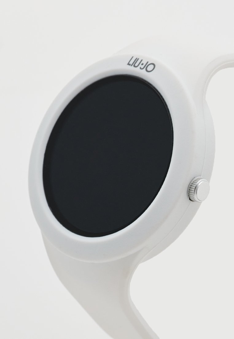 Montre en silicone blanche avec un cadran noir rond, des éléments en acier inoxydable et un design minimaliste sans marquages ni chiffres visibles.