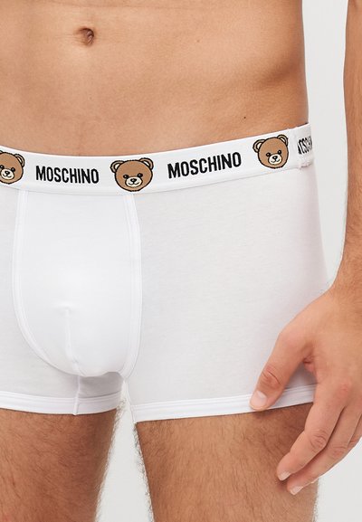 Weiße Baumwoll-Boxershorts mit einem schwarzem und braunem Bärenlogo am Bund. Glatte Textur und figurbetontes Design.