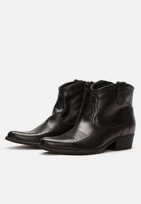 Botas de cuero negras hasta el tobillo con puntera afilada, cremallera lateral, costuras decorativas y tacón apilado. Textura suave y diseño minimalista.