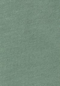 Světle zelená pletenina s jemnou a rovnoměrnou texturou, která má na celém povrchu konzistentní žebrovaný vzor.