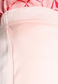 Ljust rosa satin kjol med en mjuk textur och en lätt lyster, med en ren midjeband och subtila sömnadsdetaljer.