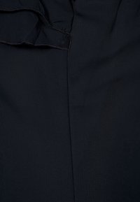 Tissu noir à texture lisse, présentant un bord froissé. Le matériau semble léger et légèrement fluide, sans motifs visibles.