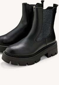 Bottines Chelsea en cuir noir avec une semelle en caoutchouc épaisse. Présentent un panneau latéral texturé avec des accents métalliques et une fermeture éclair.