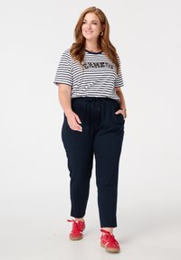  gestreepte korte mouwen t-shirt met een grafisch ontwerp, gecombineerd met marineblauwe elastische taille broek en rode veterschoenen. Eenvoudige en casual outfit.